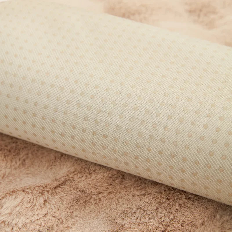 Zoom sur le tissu d'une housse de canapé en fausse fourrure beige, mettant en évidence la texture douce et les points de latex antidérapants sur le revers, garantissant la qualité et la fonctionnalité du produit.